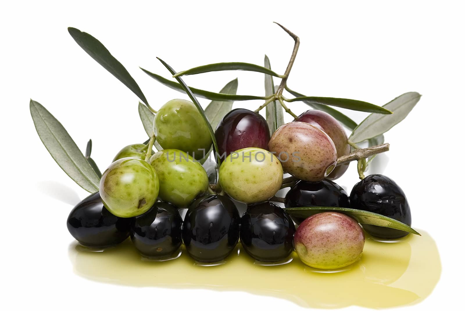 Some olives with branches and leaves and some olive oil.