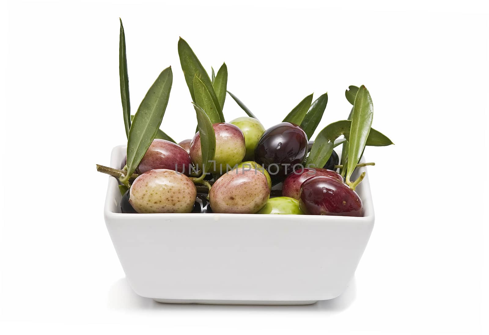 A white bowl full of olives and leaves.