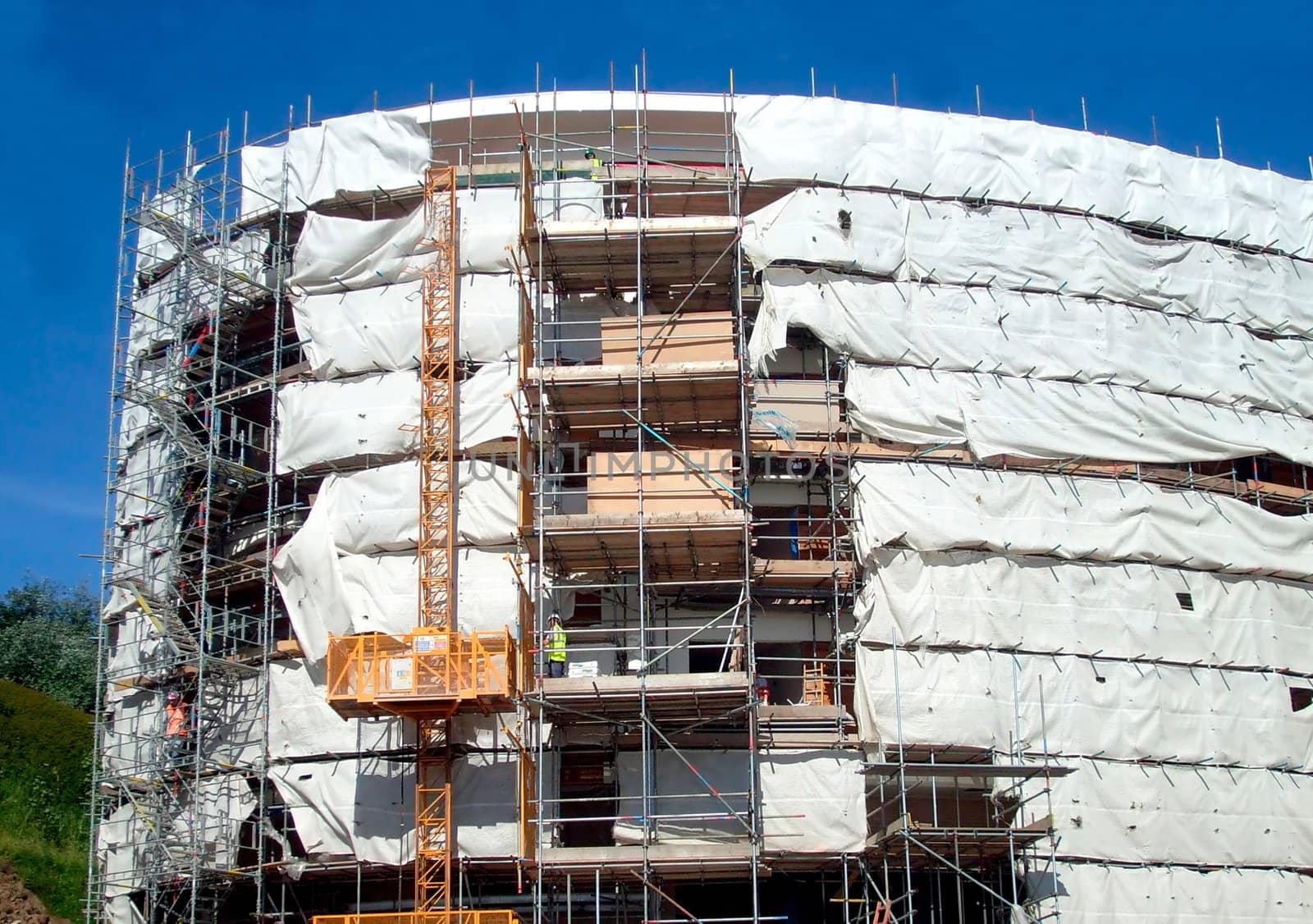 A general view of the exterior of a new modern building site development covered in scaffolding and cladding.