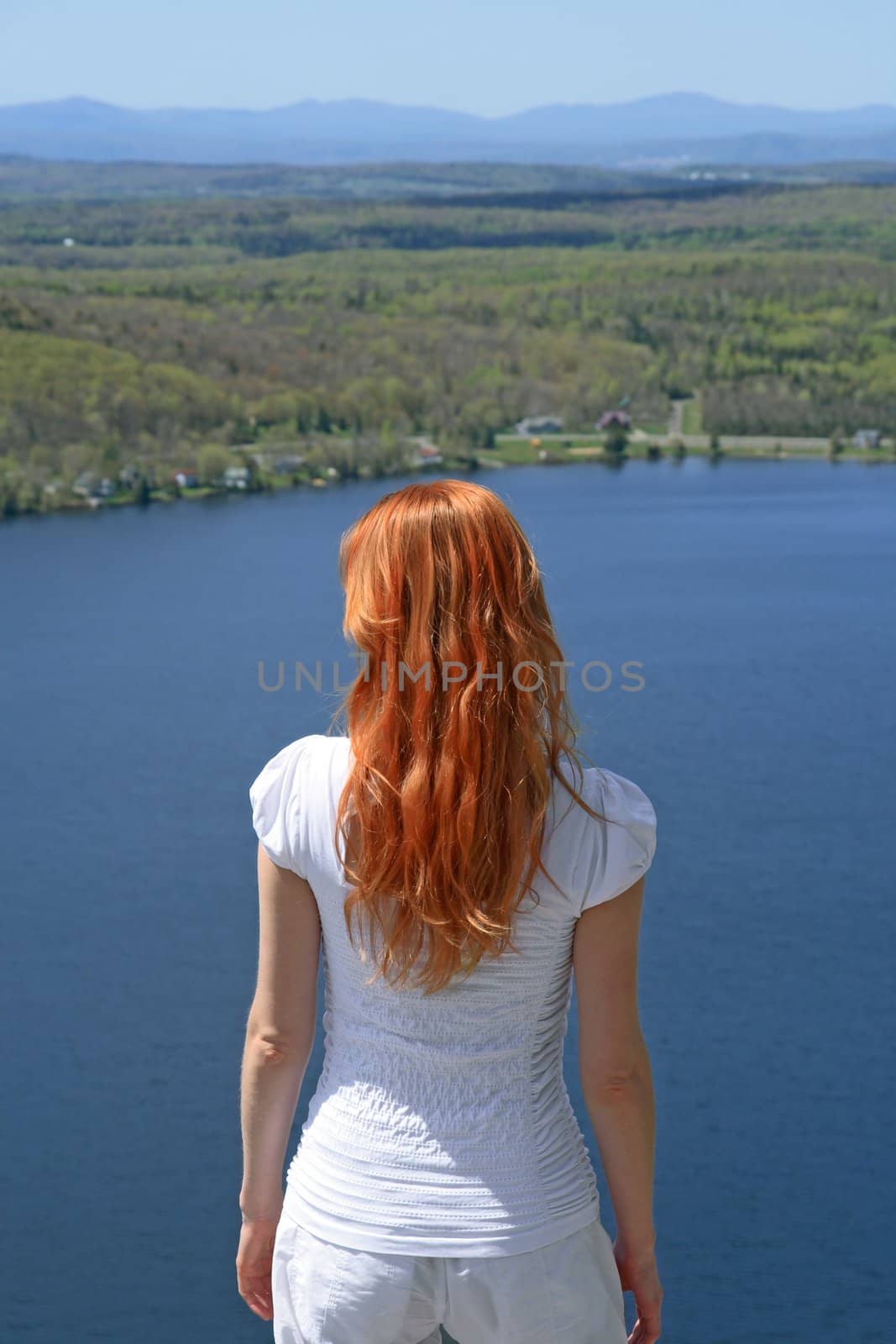 Red-haired girl looking over blue lake by anikasalsera