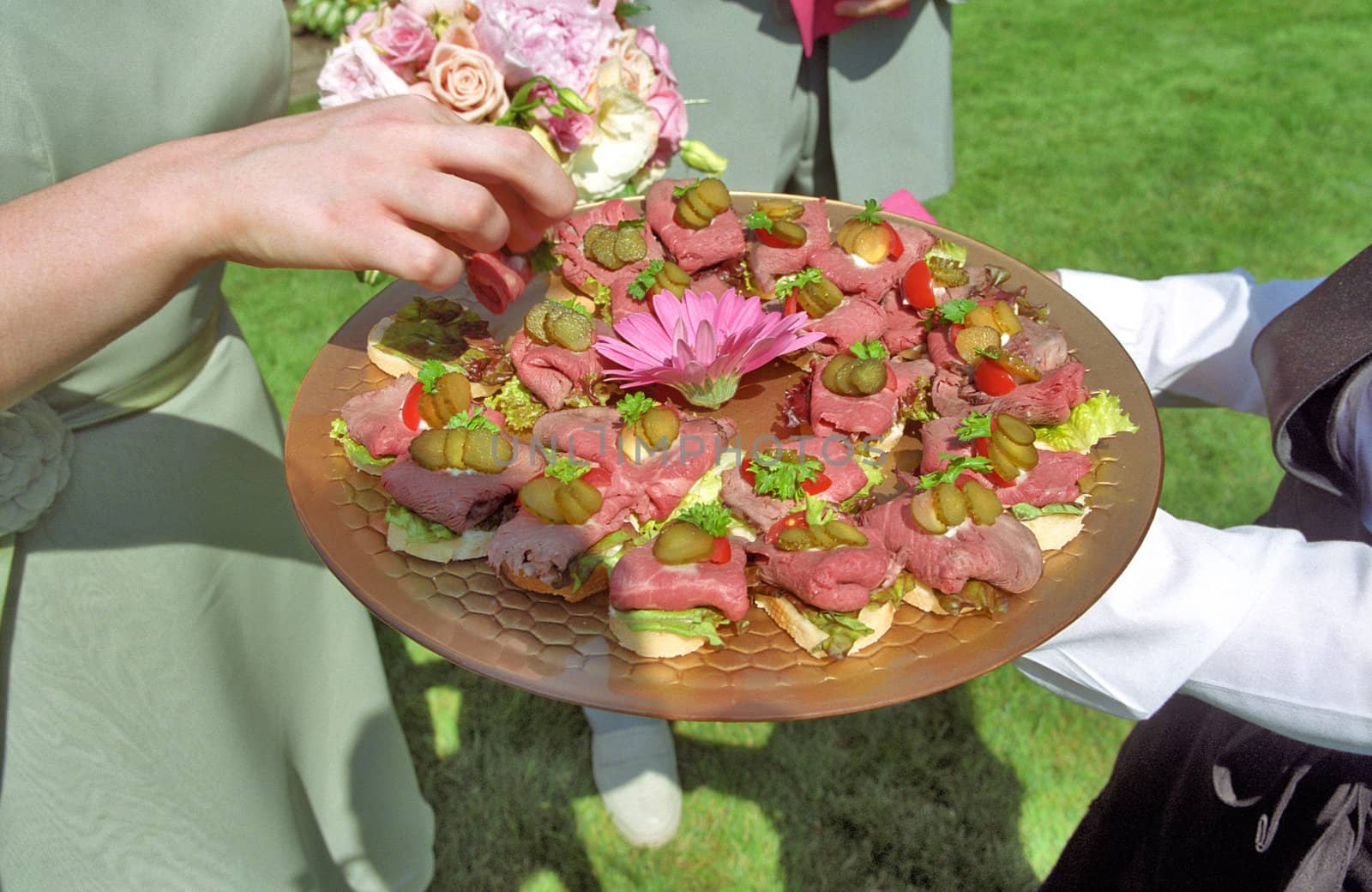 A bridesmaid takes an hors d'oeuvre at an outdoor wedding reception.