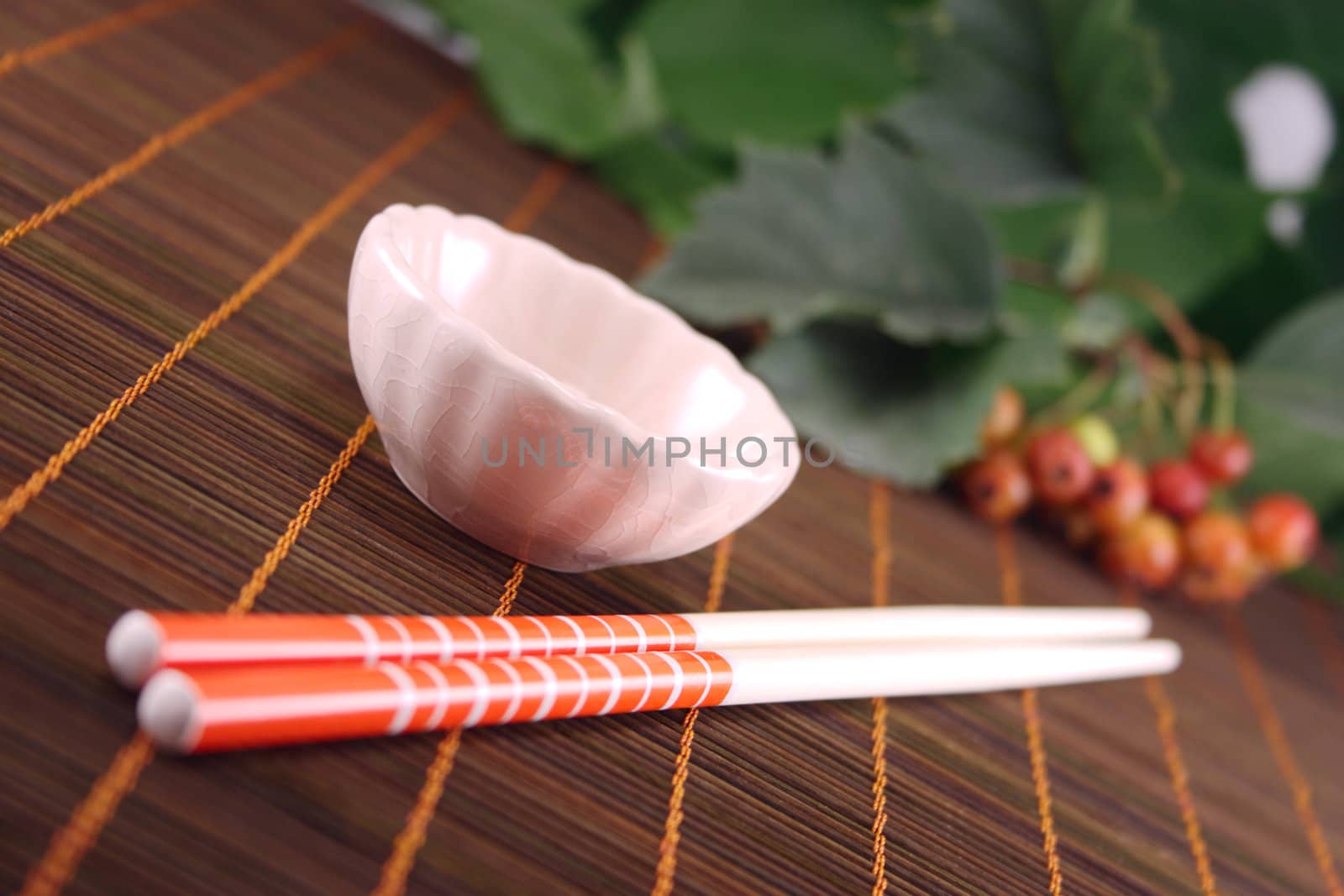 Cup and chopsticks on a wooden napkin against plants