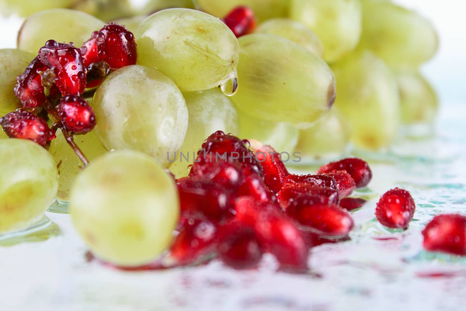 Grapes with pomegranate grains on glass removed close up