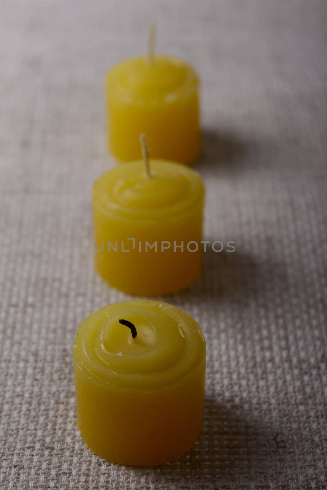 Three tea candles on a linen napkin removed close up