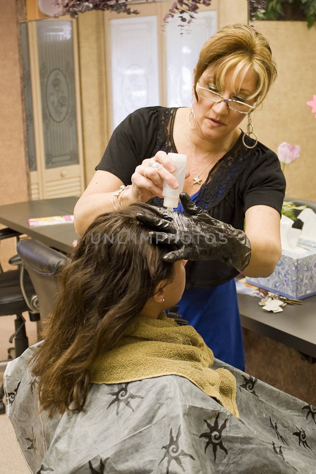 A hairdresser working on a clients hair color at the salon.