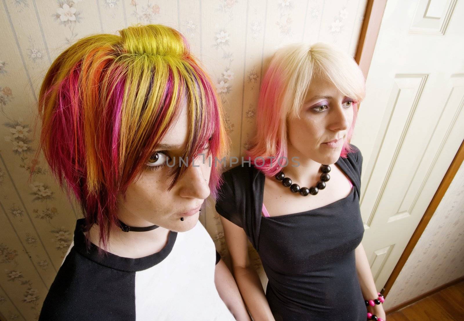 Women in colorful hair leaning a wall in a hallway