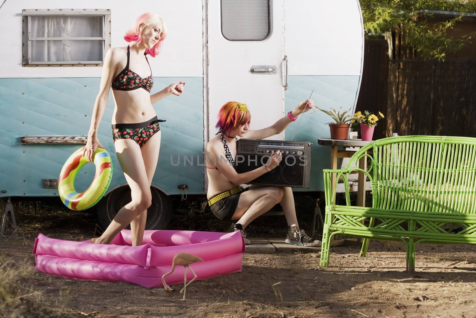 Women doing summer activities outside a travel trailer