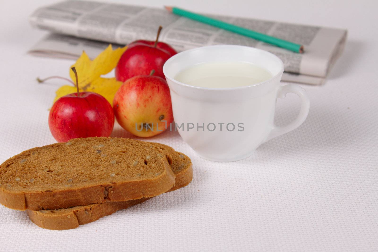 Bread with milk and apples against a morning paper removed close up