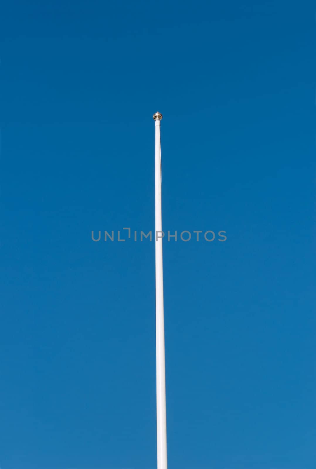 Empty flagpole against deep blue sky.
