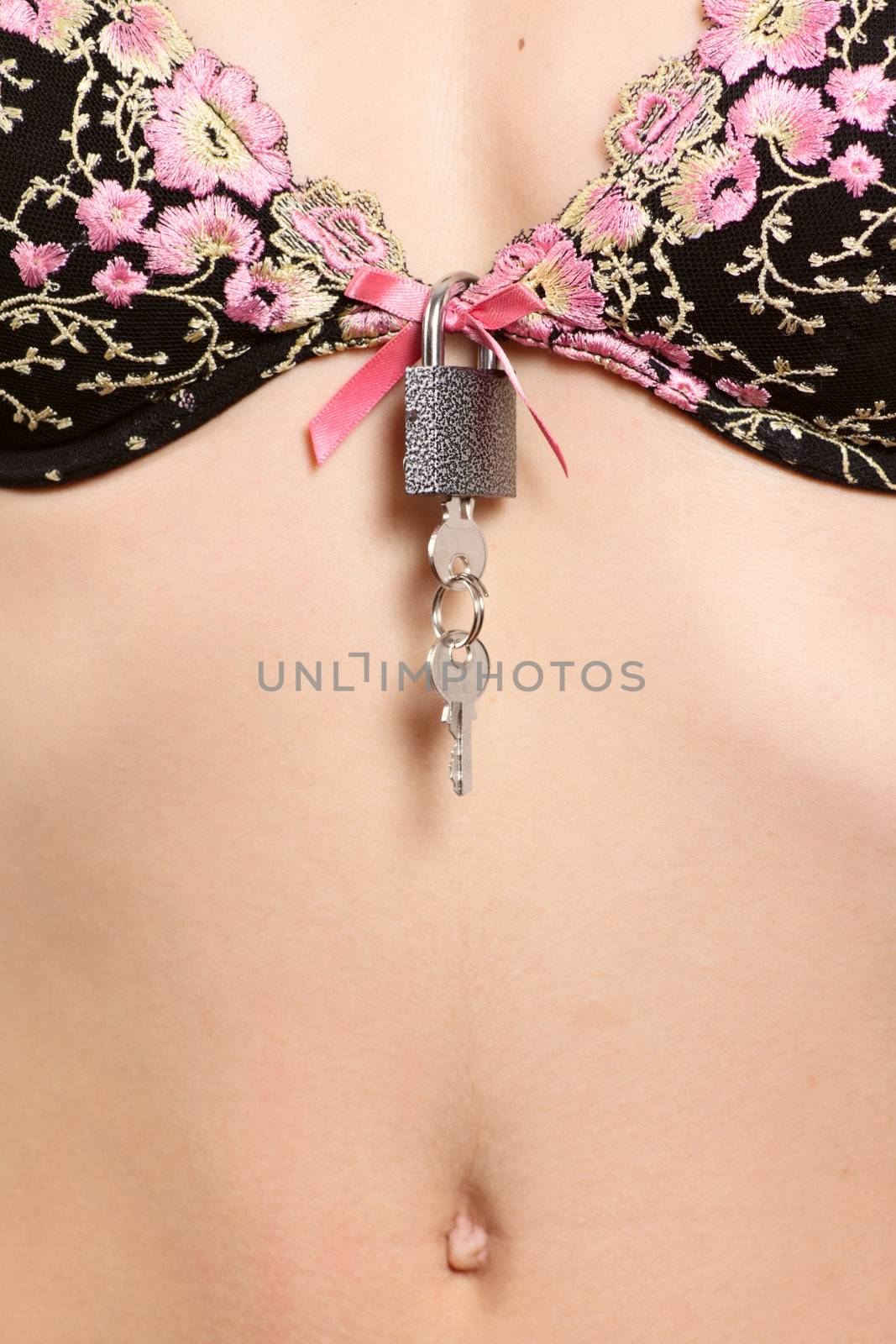 Breast of the girl in bra with a padlock and keys removed close up