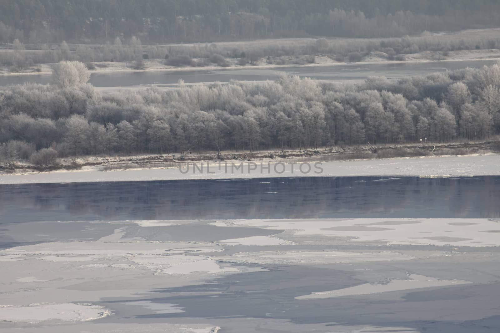 The stood river removed in winter cloudy day with snow covered trees on coast