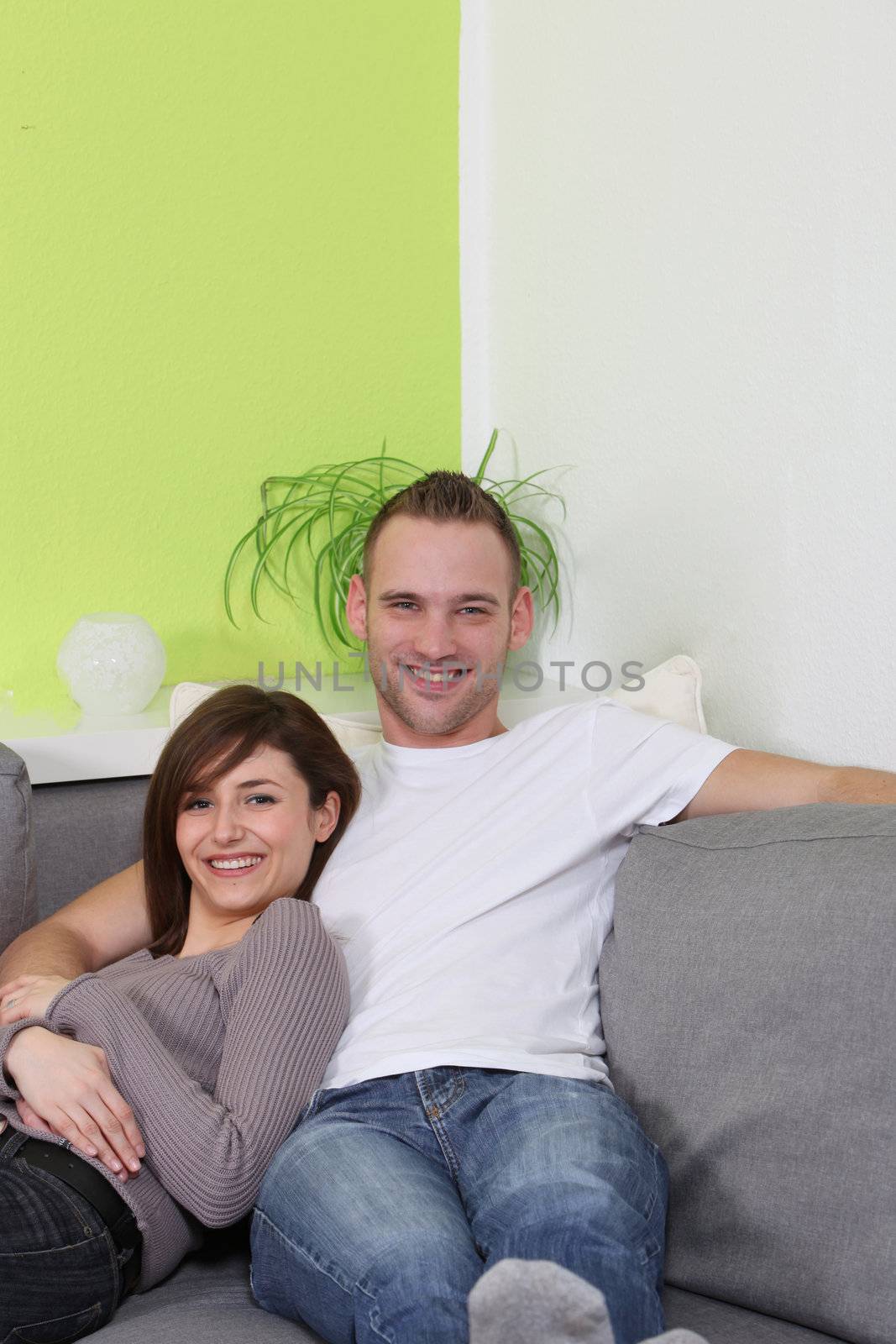 Young, happy couple relaxing at home. It sits comfortably on the sofa