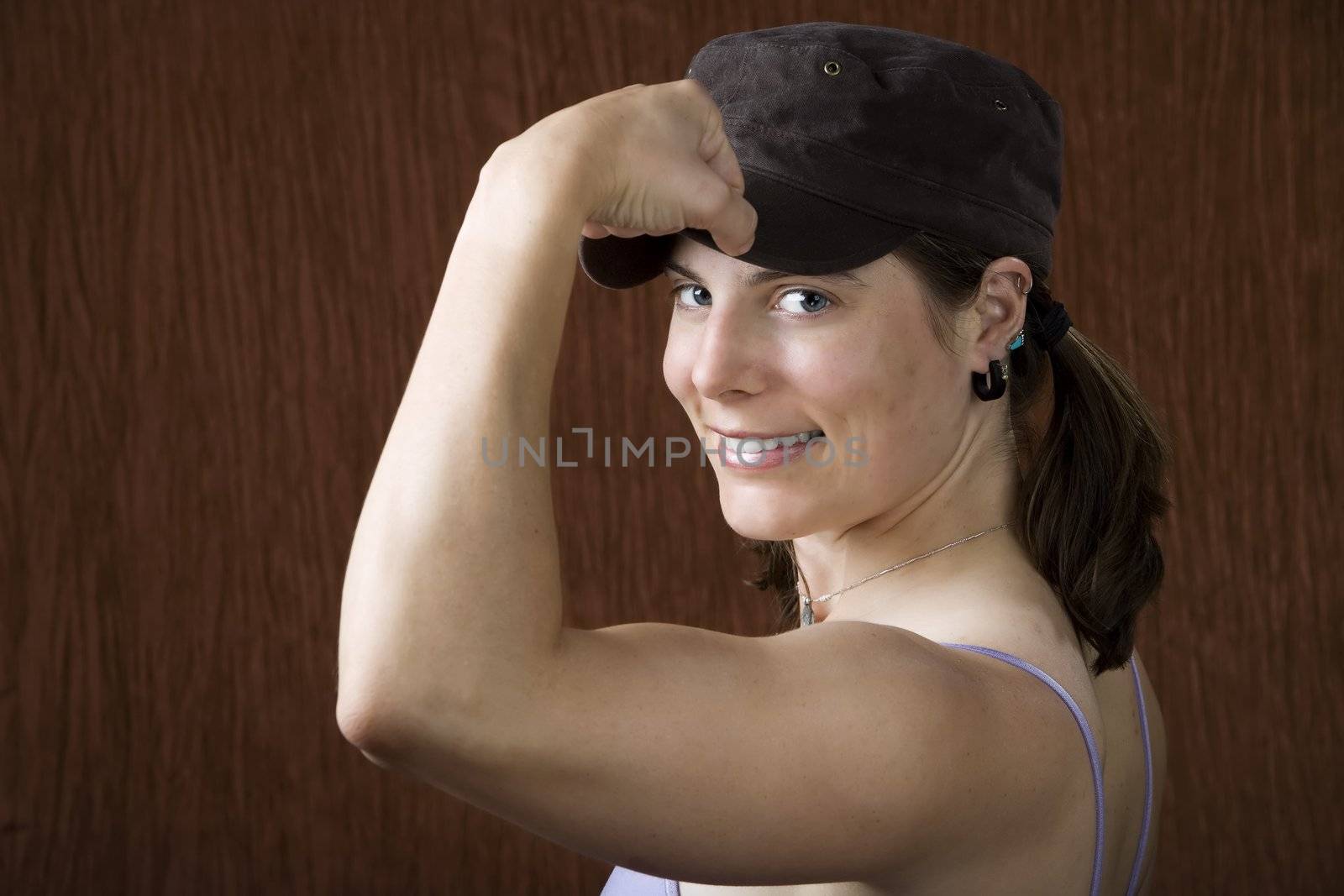 Closeup of woman with blue eyes wearing a cap flexing her bicep