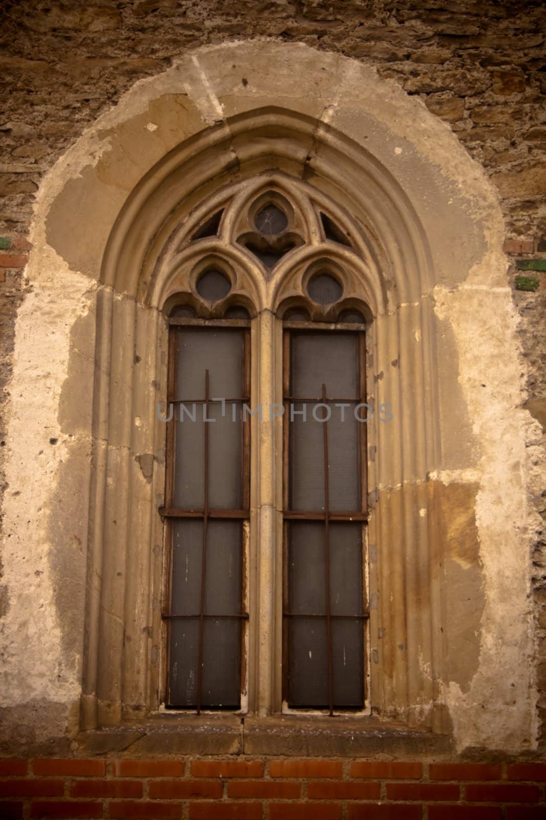 Beautiful stone thin window with Gothic archs, stone bricks surround