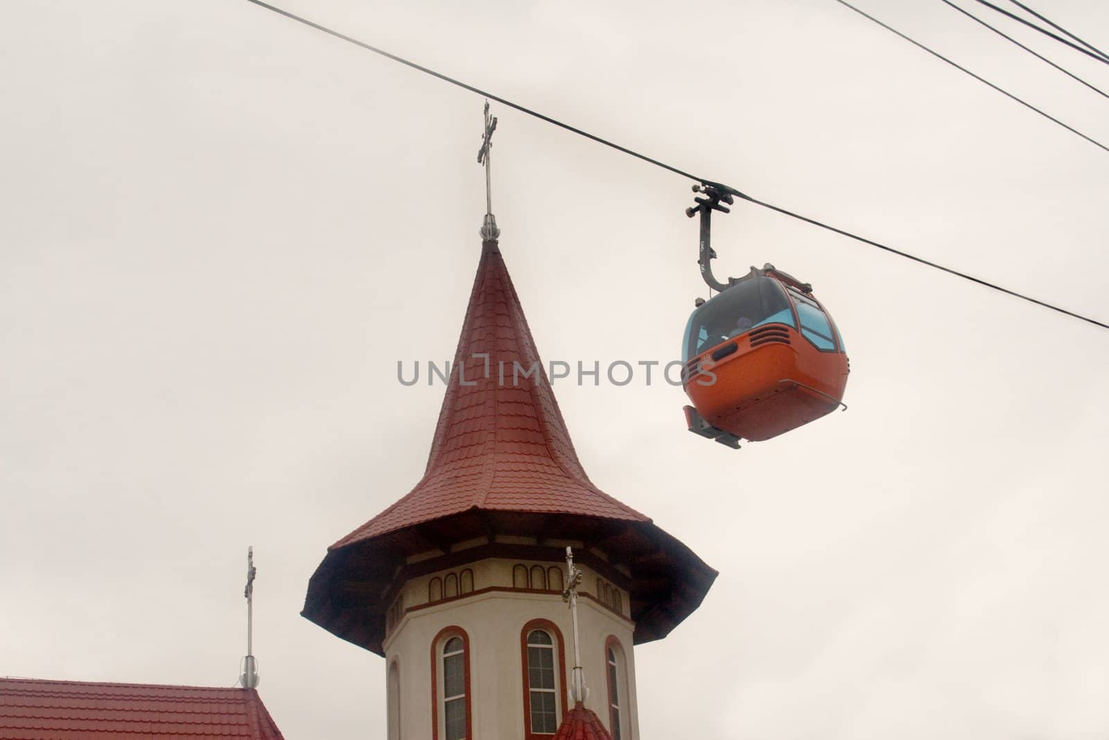 Ski gondola traveling low and past the top of a church