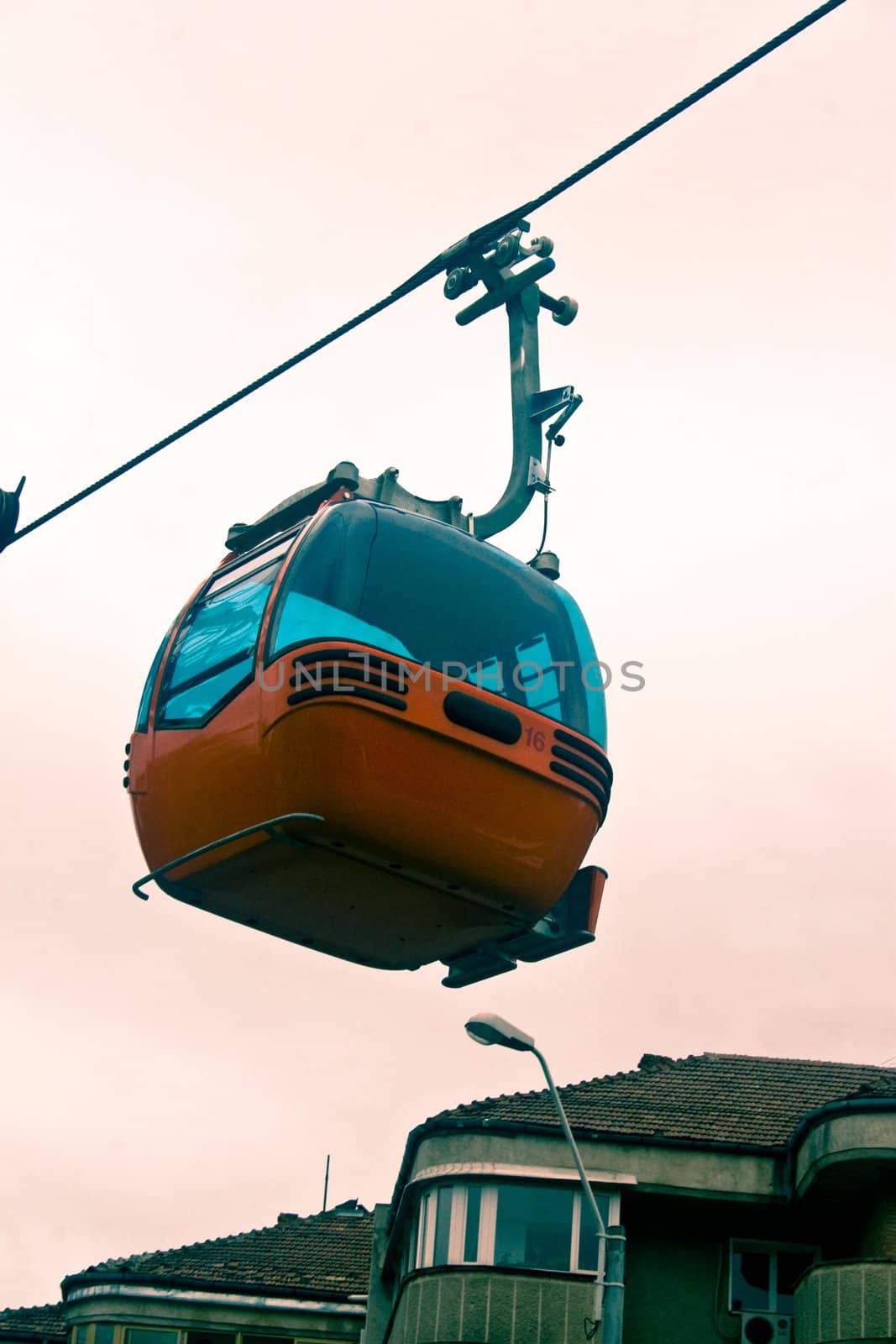 Ski gondola traveling low and past apartment buildings