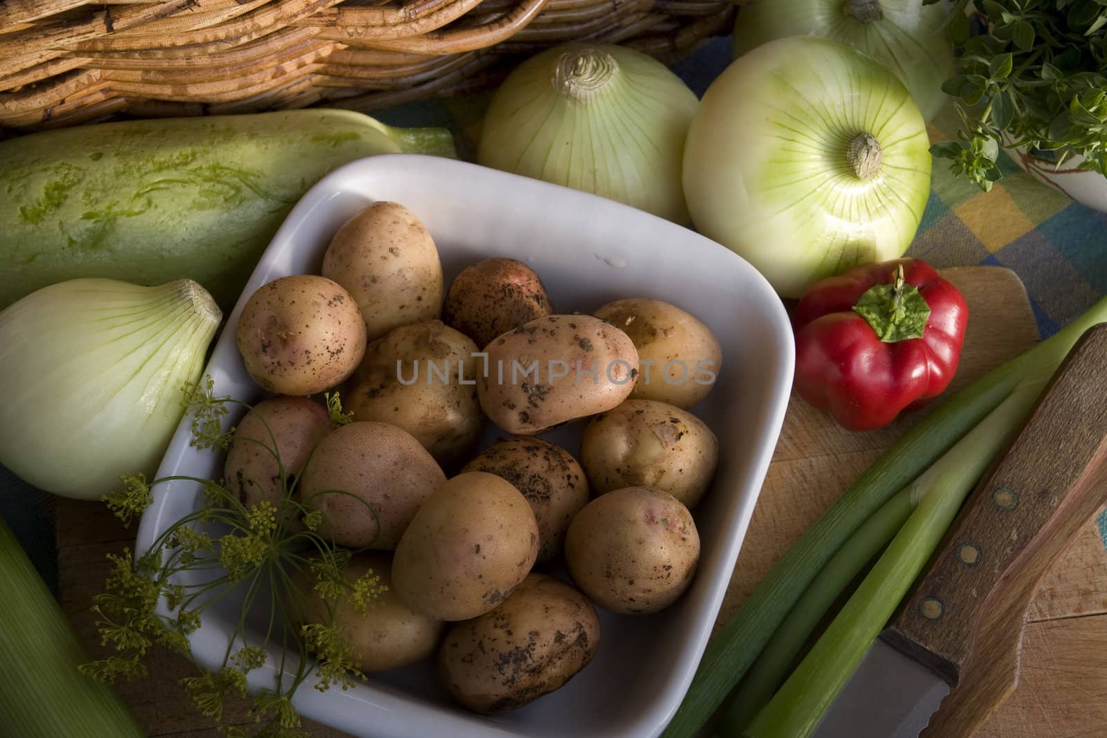 Dish of young, fresh potatoes and other vegetables on the rustic desk