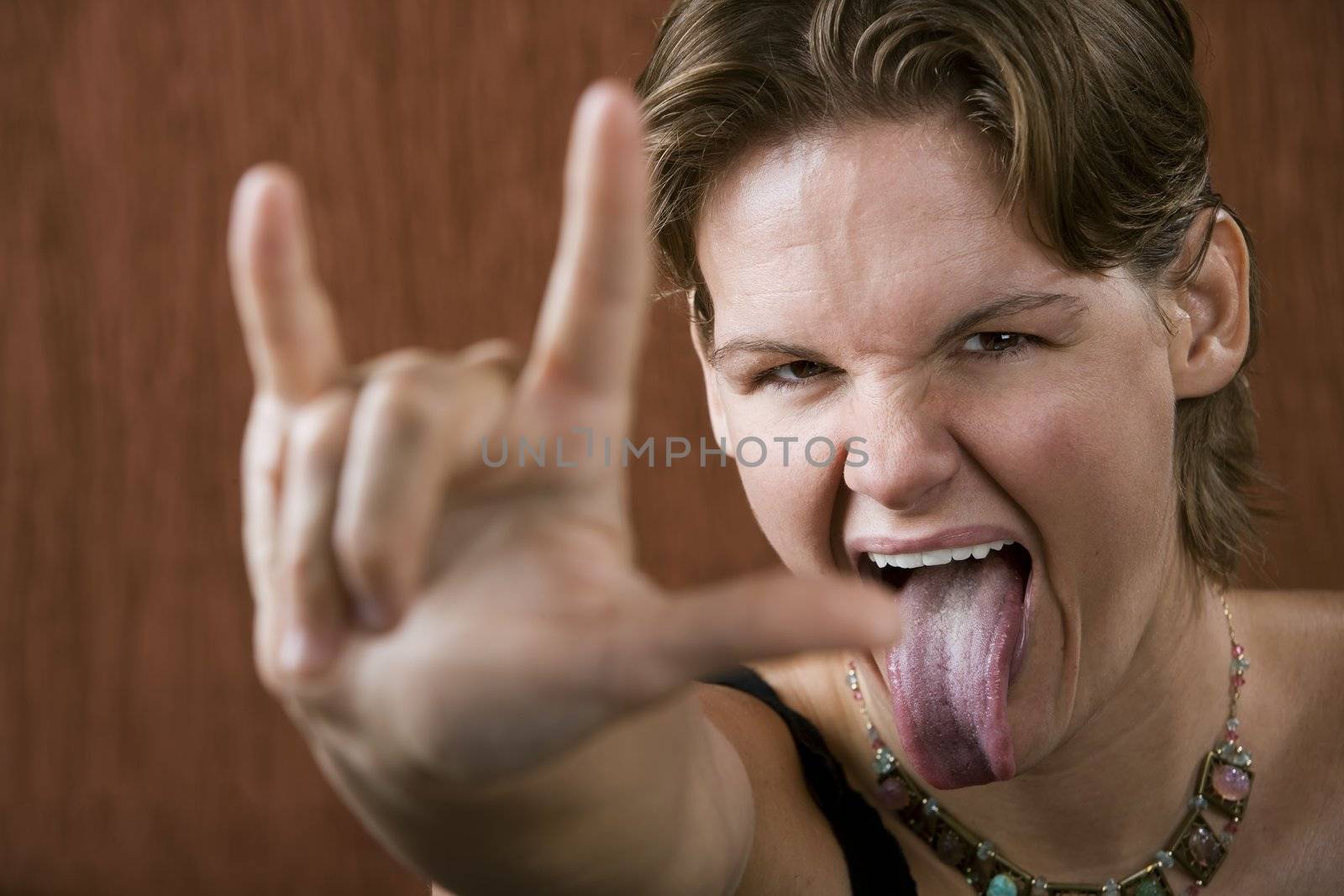 Attractive woman making bull horns and sticking out her tongue