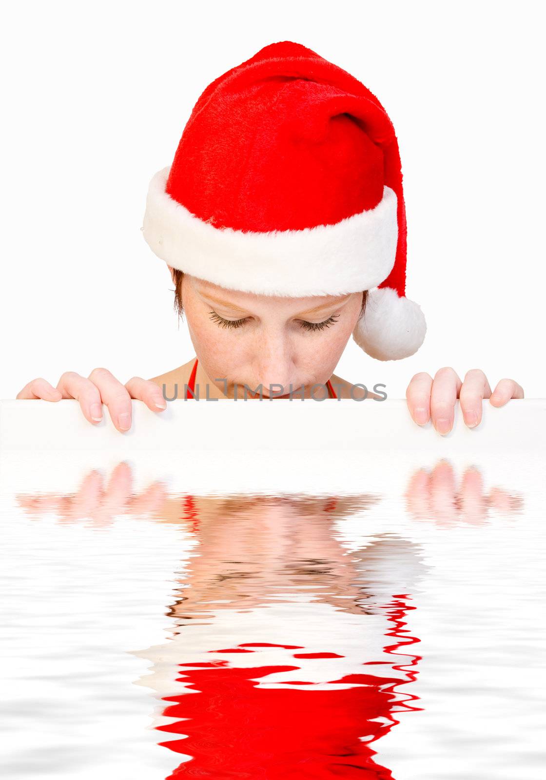 Beautiful girl in christmas bikini and with christmas hat is holding up a white sign for copy space. With background clipping path for your convenience
