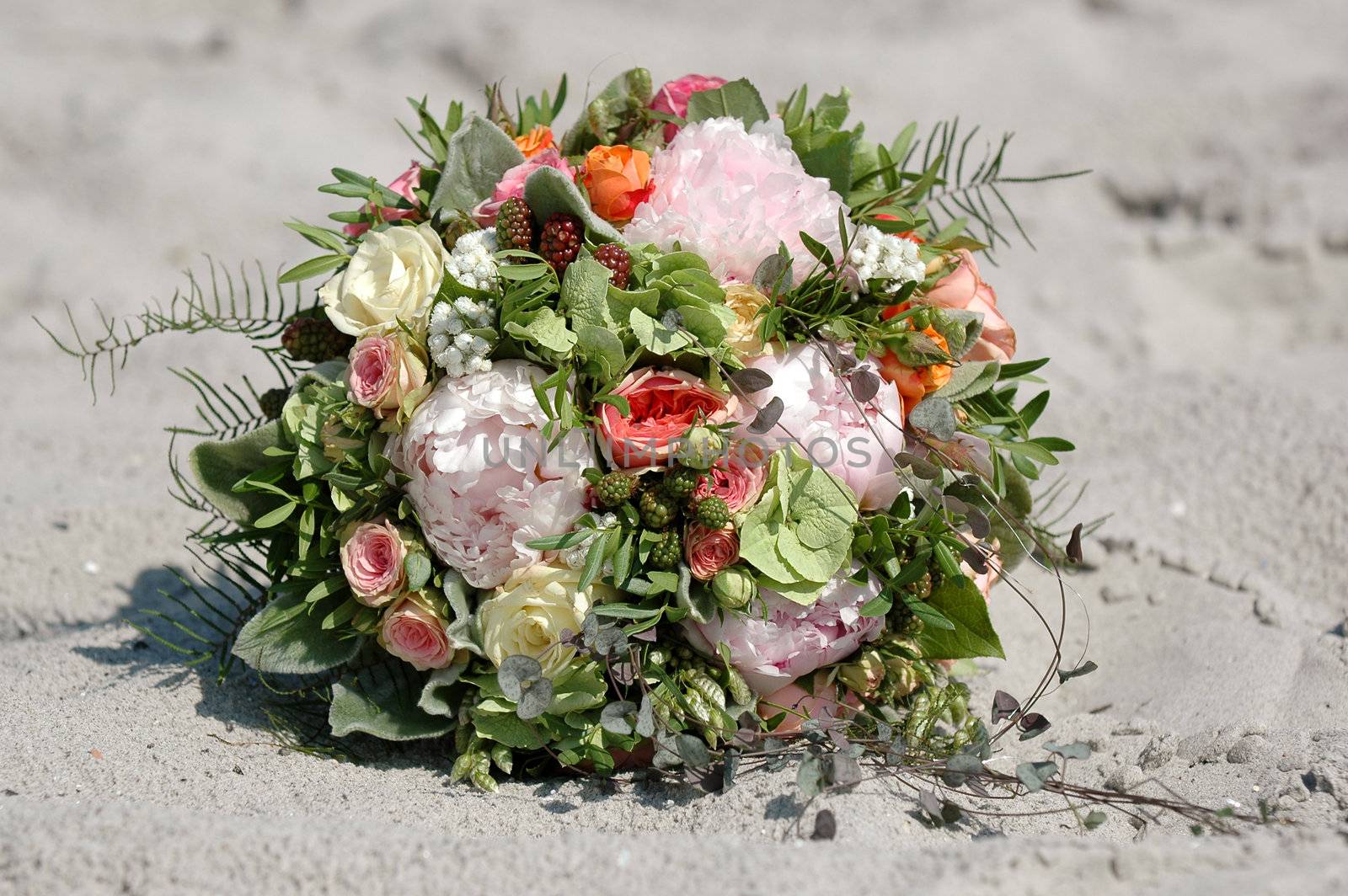 Wedding flower bouquet. The flowers are lying in the sand.