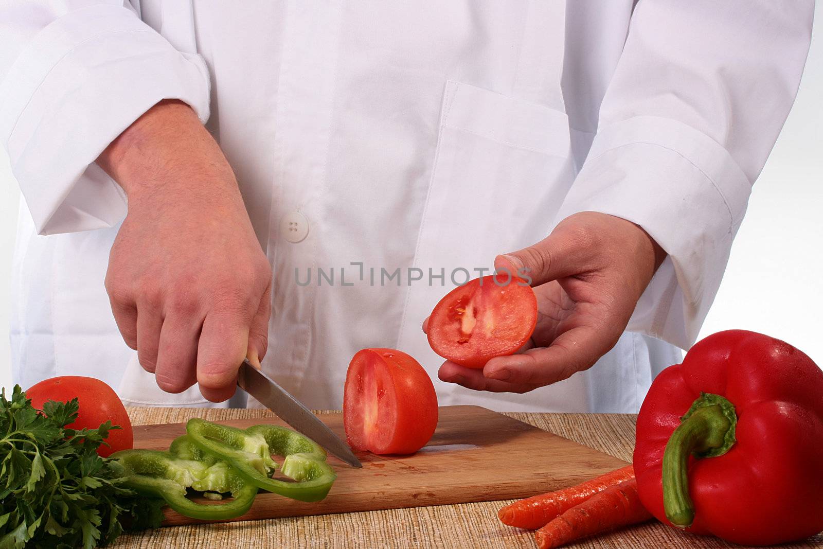 The cook having cut a tomato shows the cut off part.