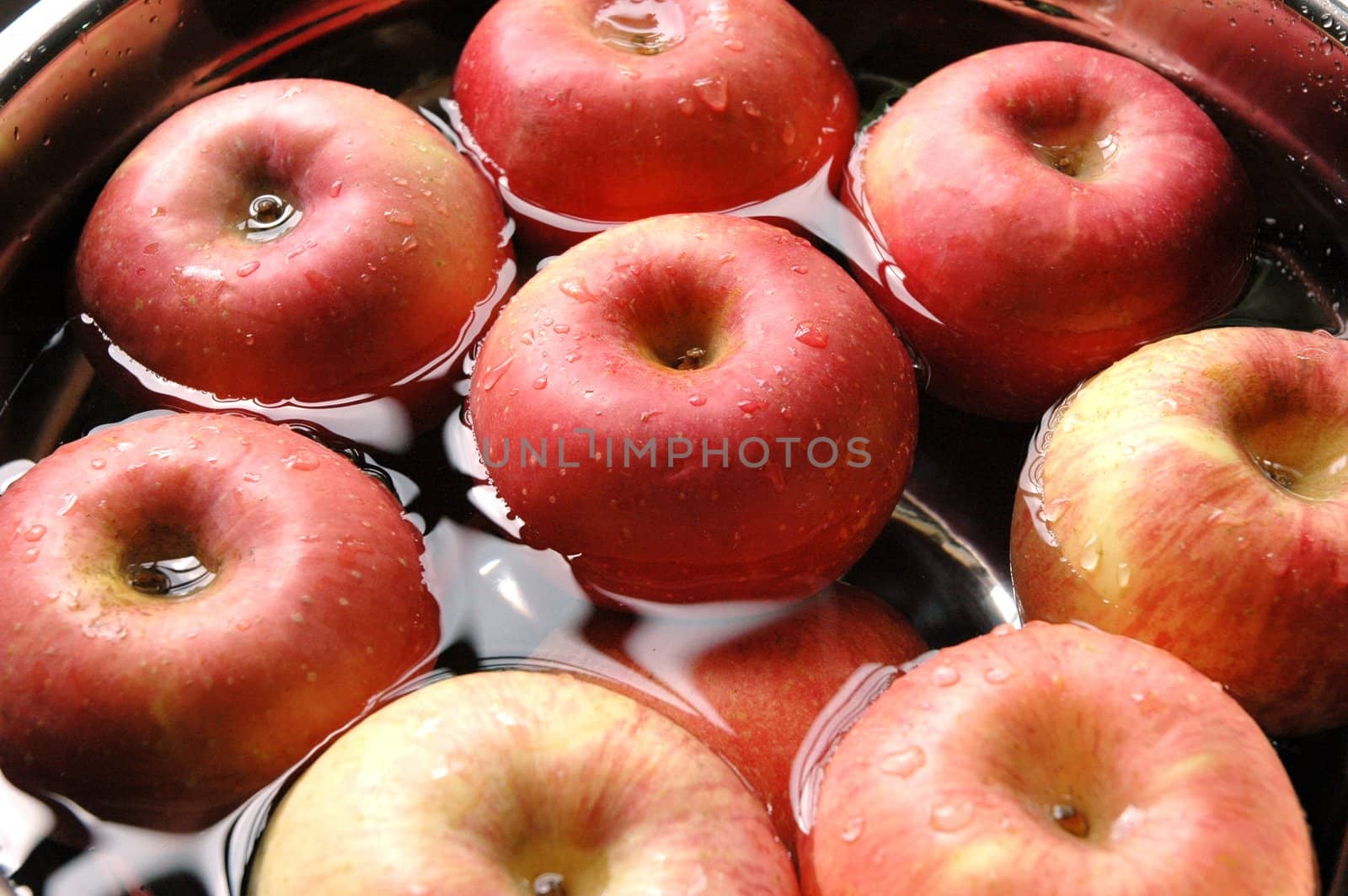 Fresh red apples floating on water in container