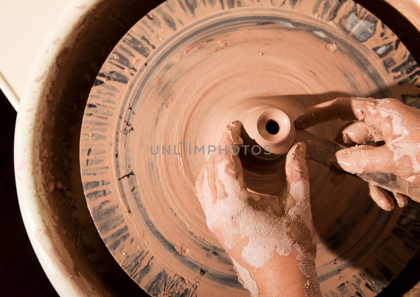 Overhead shot of potters hands with file shaping vase