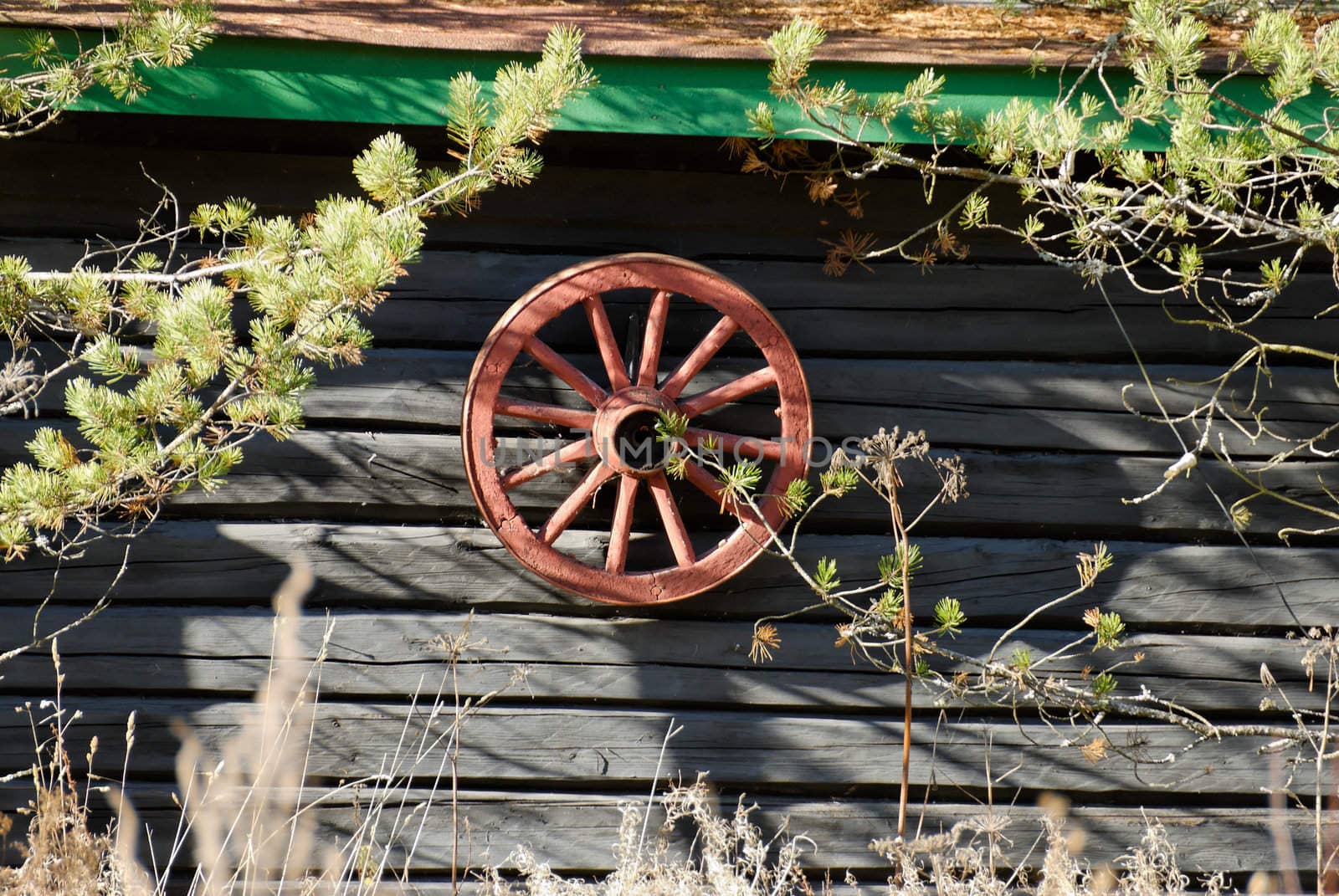 Red cartwheel hanging on a old house wall
