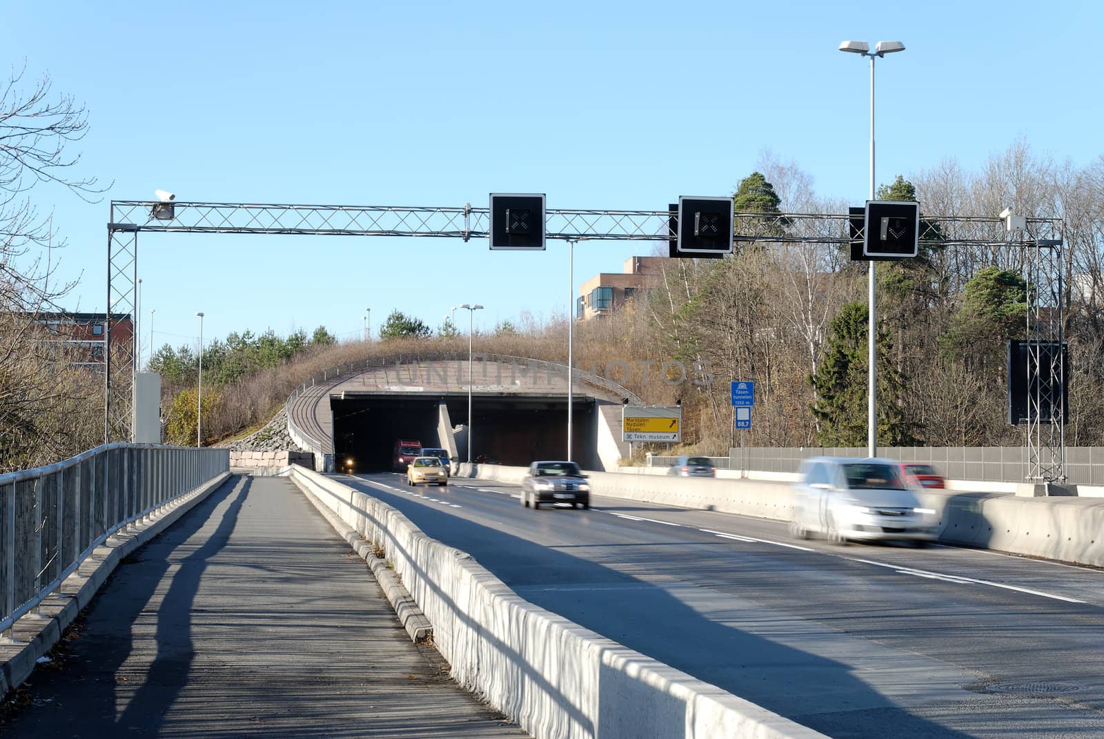 A highway tunnel with cars speeding out of it. Nydalen, Oslo, Norway
