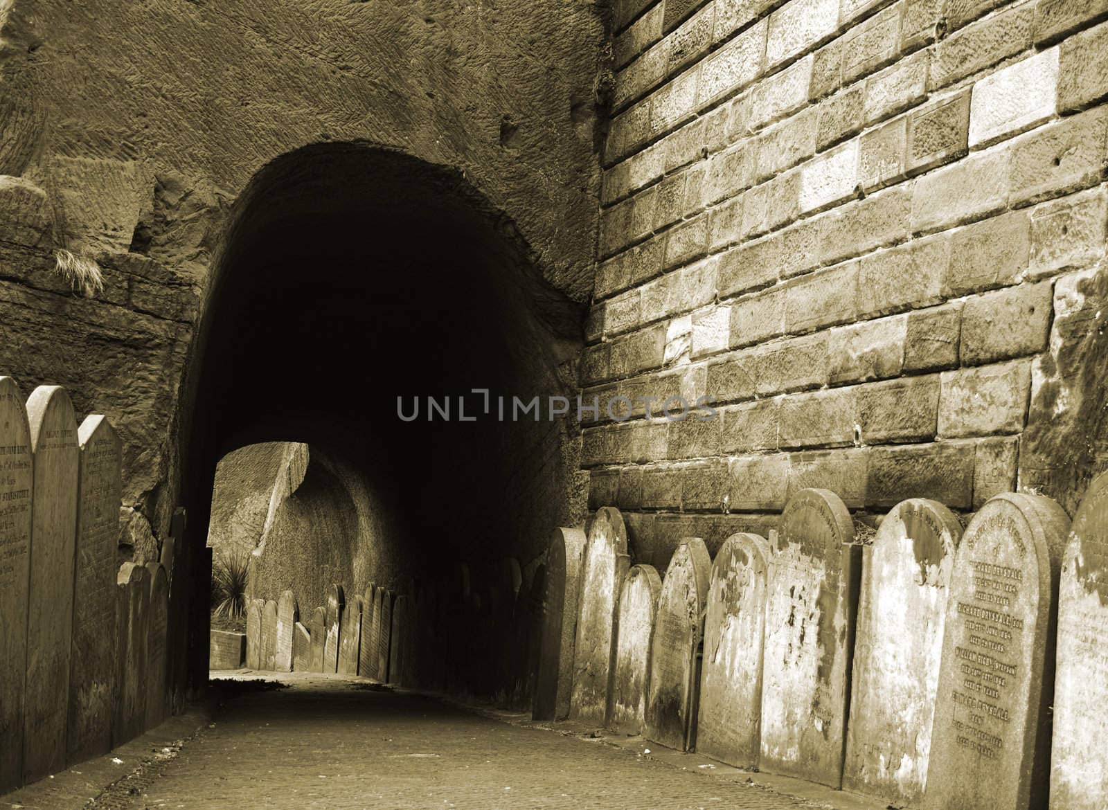 Row of very old tombstones leading into a tunnel