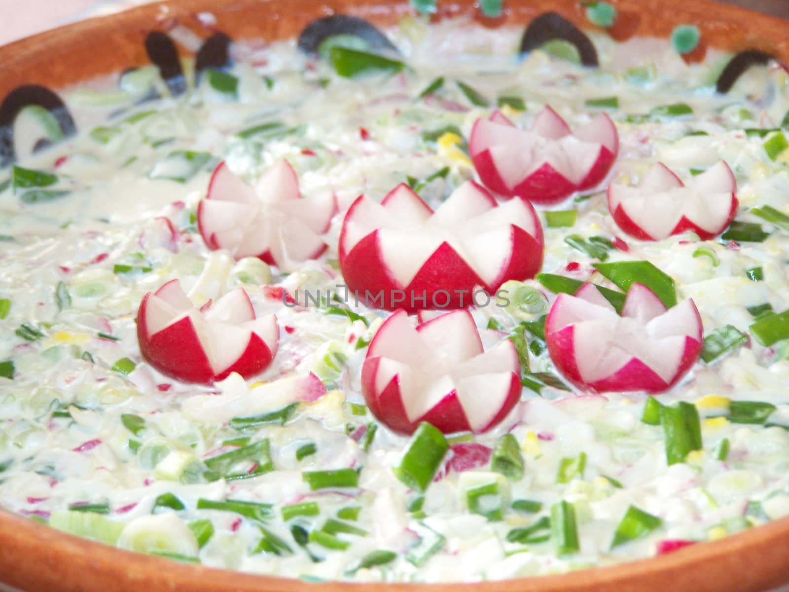 Spring salad decorated with reddish. Made of onion, boiled eggs, reddish, cucumbers and sourcream,