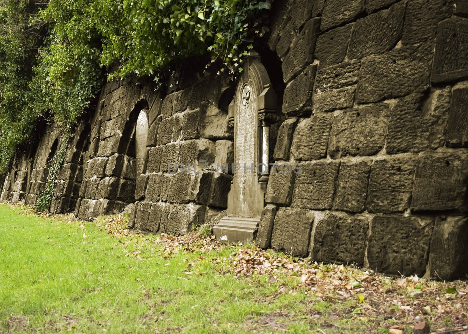 Row of very old tombstones leading into a tunnel