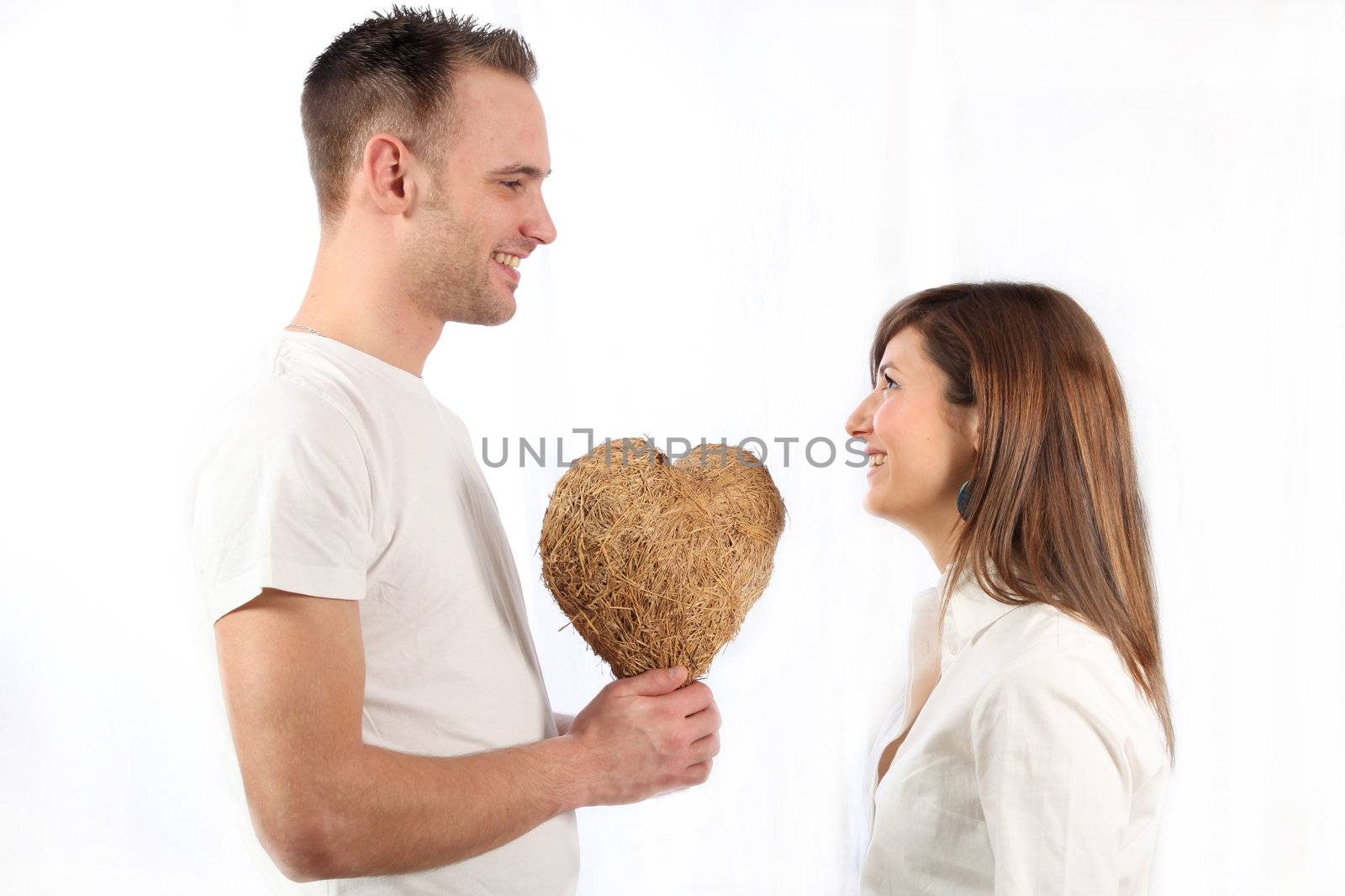 Young man handed smile of a young woman a heart made of straw and both