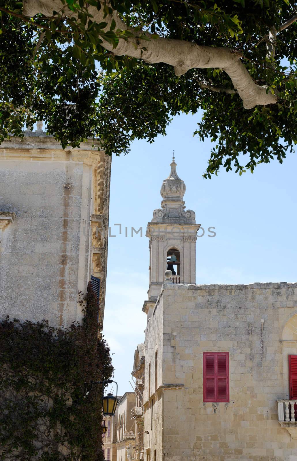 Bell ower of Carmelite church, seen from Pjazza tas-Sur, framed by a tree branch. Taken in Mdina, Malta.
