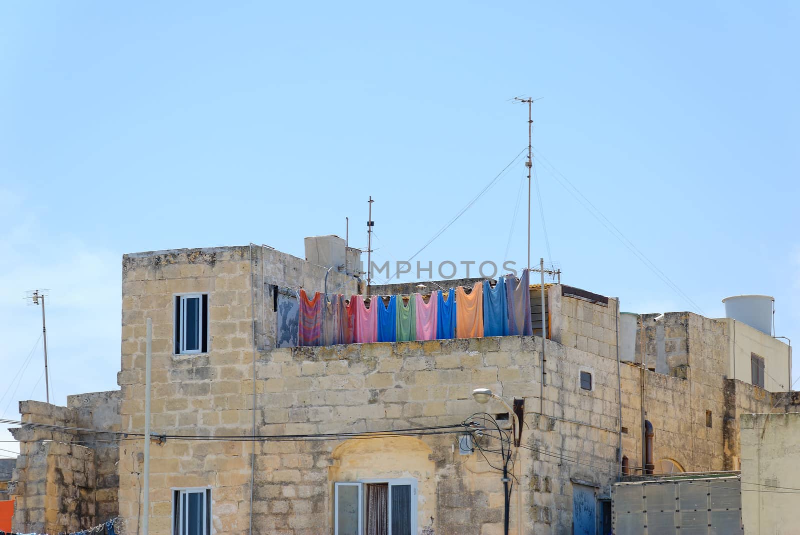 Multicoloured laundry, hanging for drying on a balcony of a Maltese house in Mdina.
