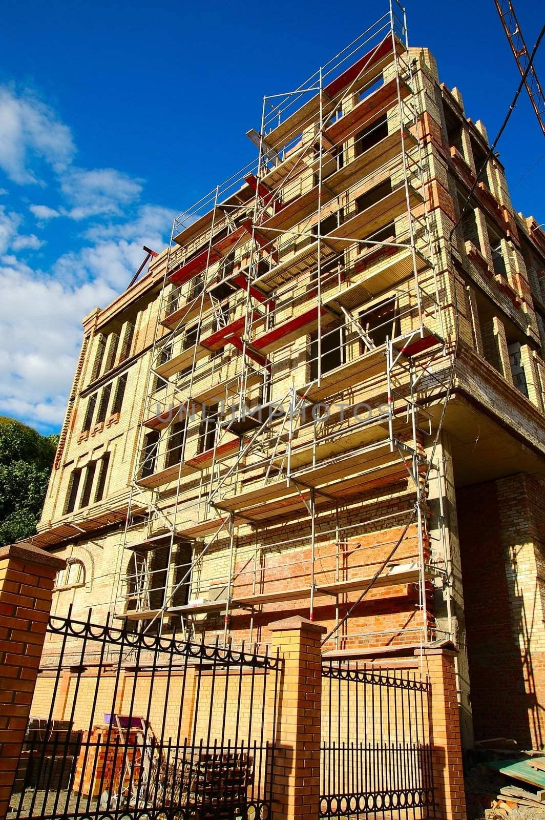 Brick building with falsework under construction against blue sky