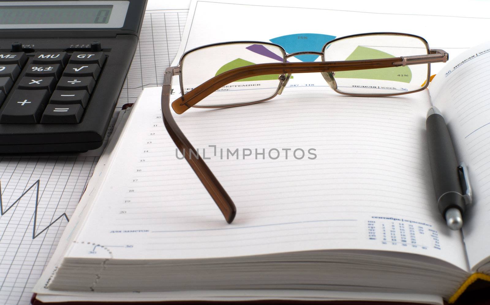 White-collar jobs, glasses and pen on an open notebook, schedule and calculator.