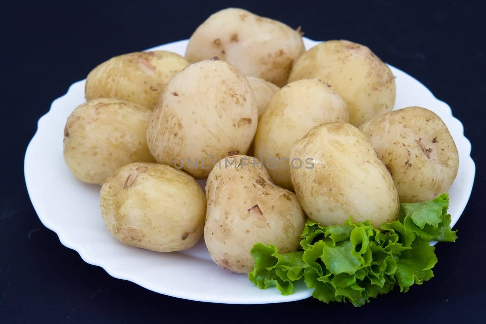 Potatoes on a white plate on a black background