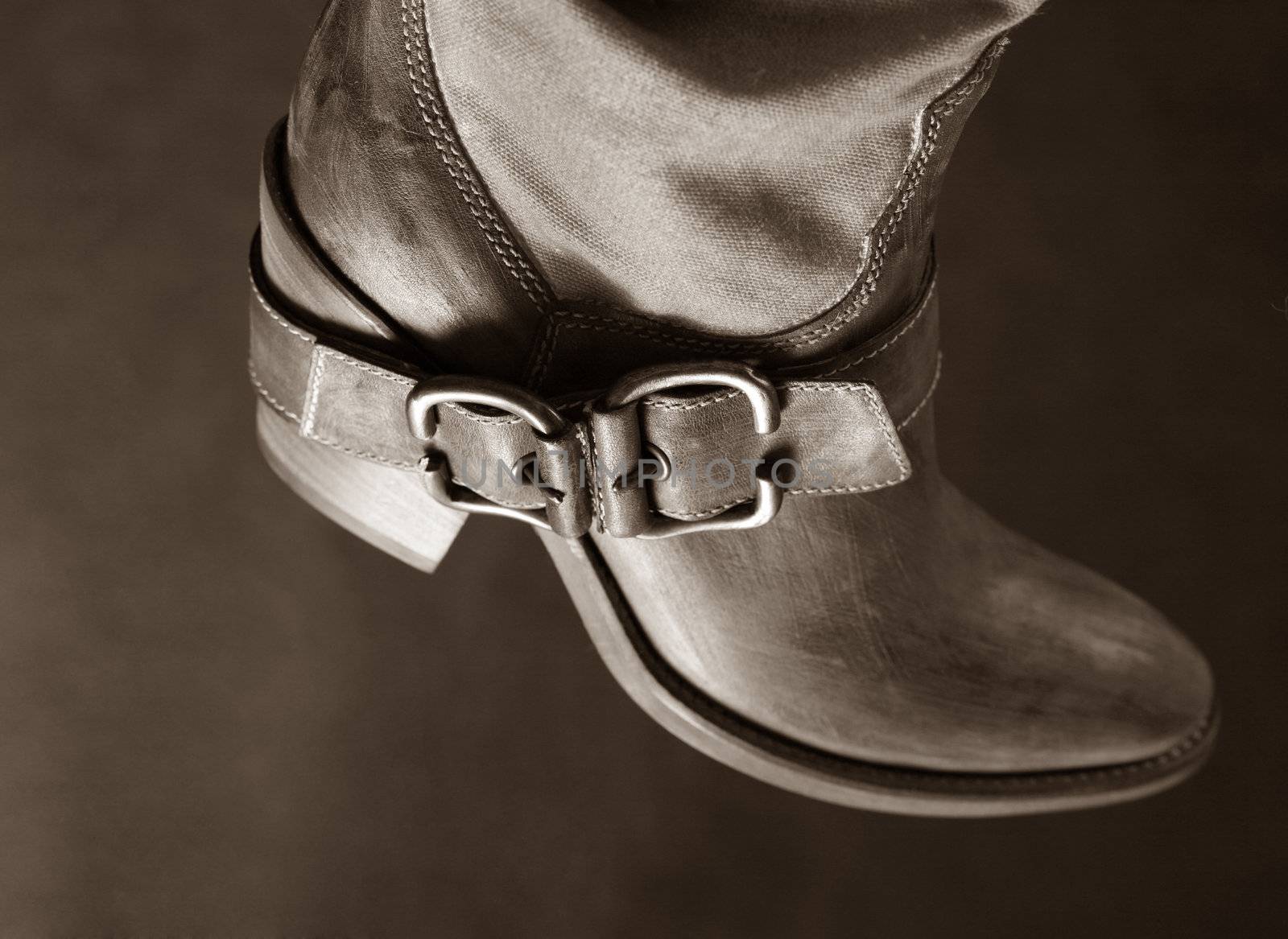 Female boot of the cowboy on a dark background