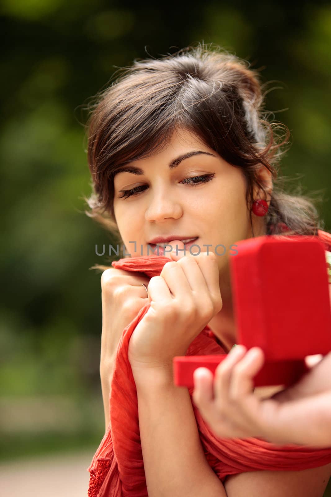 young attractive girl looking at red ring box presented to her by someone