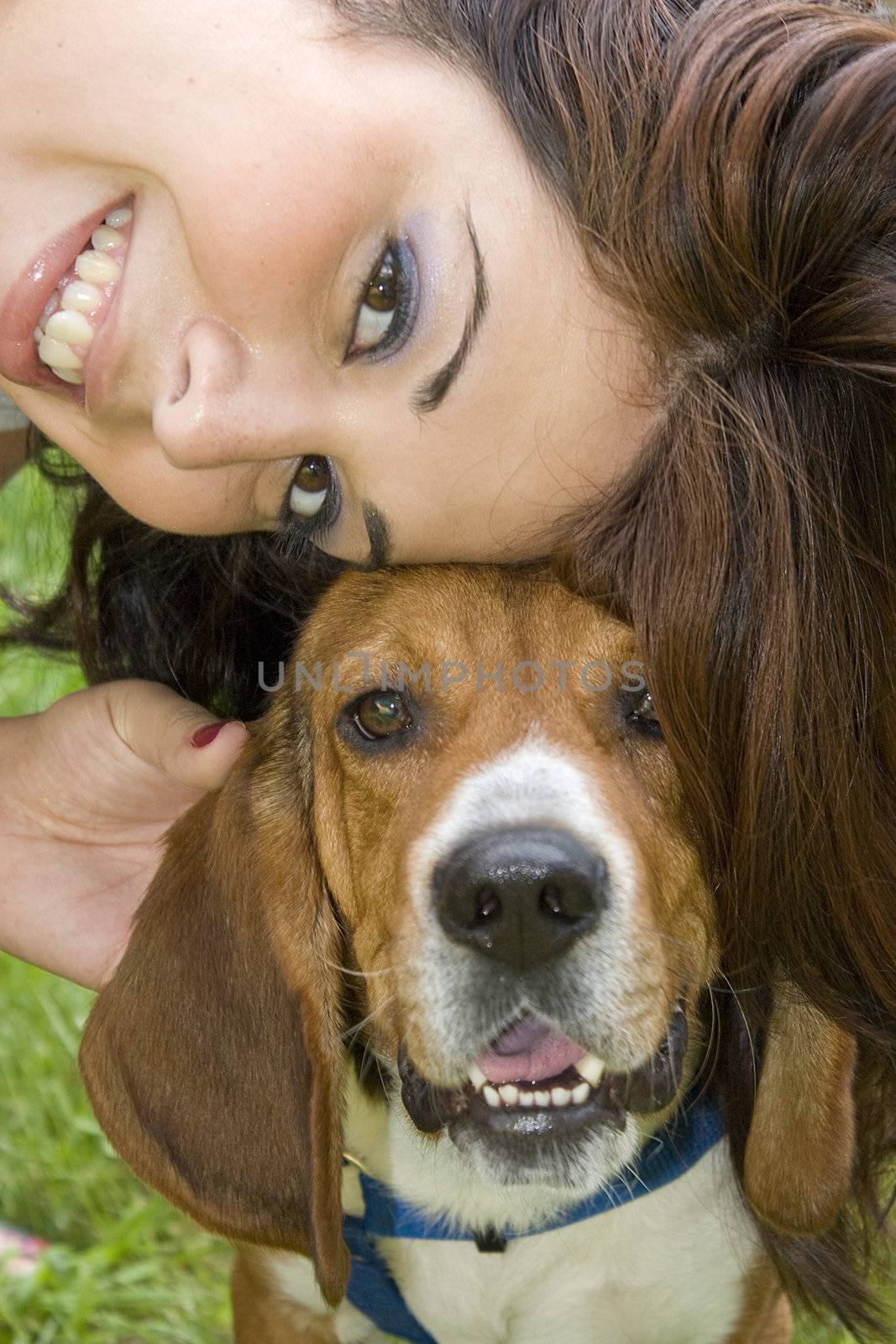 A pretty girl posing with her beagle dog - they both seem to be smiling.