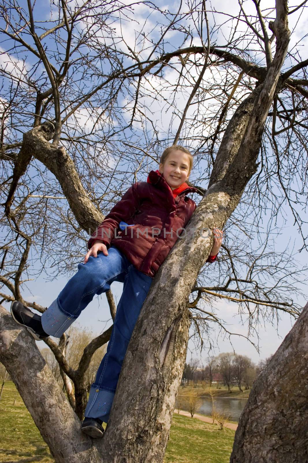 Girl will climb on tree. City park. Spring time.