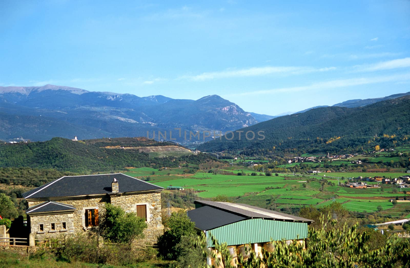A stone farmhouse sits in a valley in the Pyrenees mountain range in Spain.