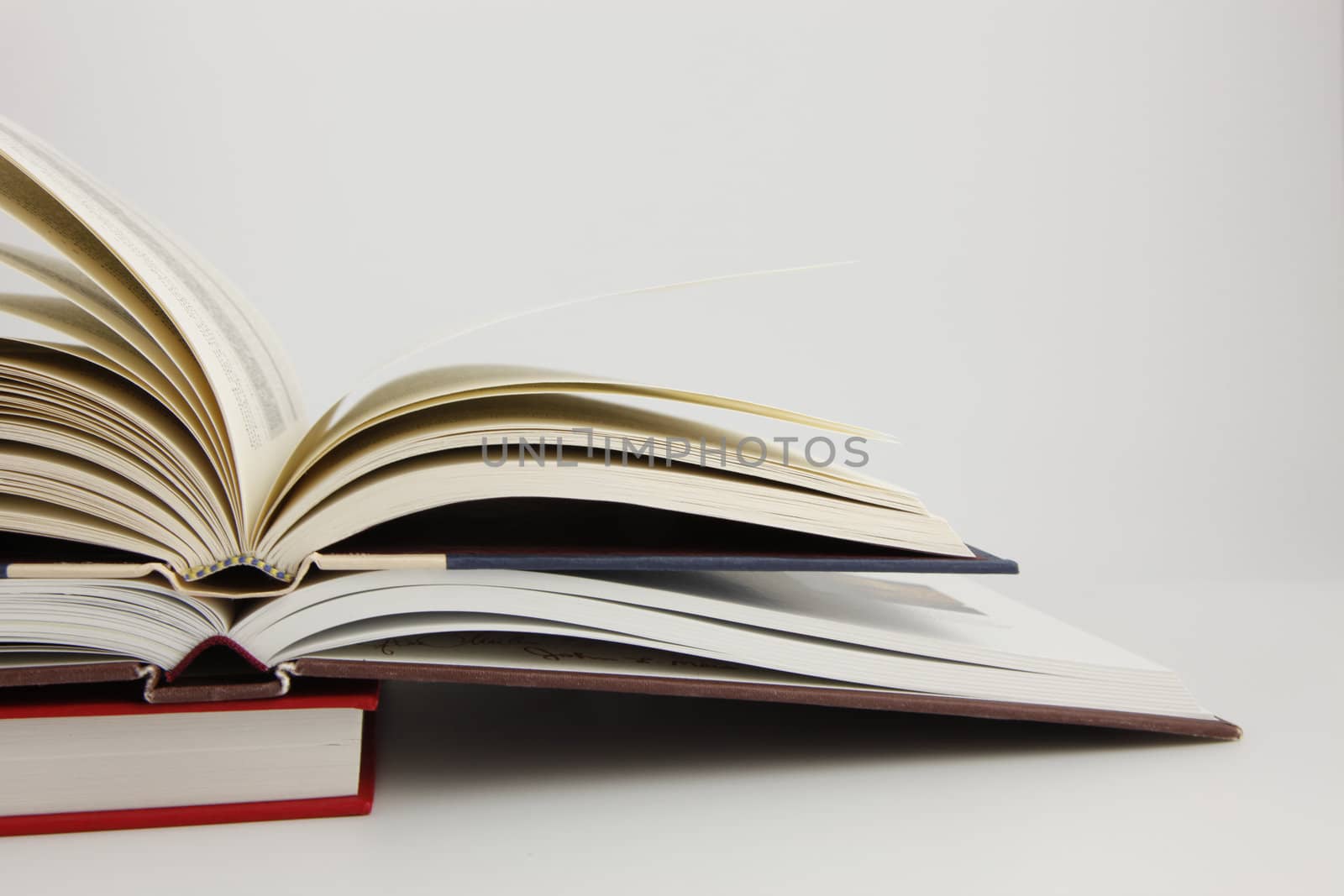 Two open books on a third closed book with a white background