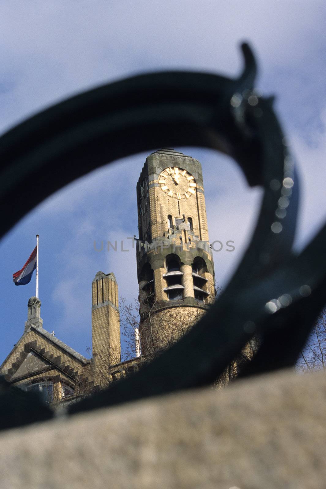 A unique view of the clock tower of the famous American Hotel in Amsterdam, the Netherlands which stands beside dutch flags on Singelgracht.