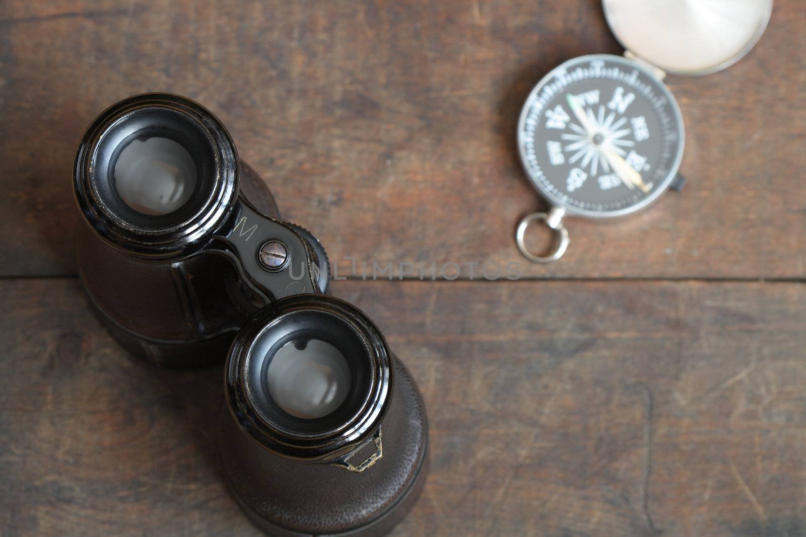 Still life with antique binoculars and compass on wooden background