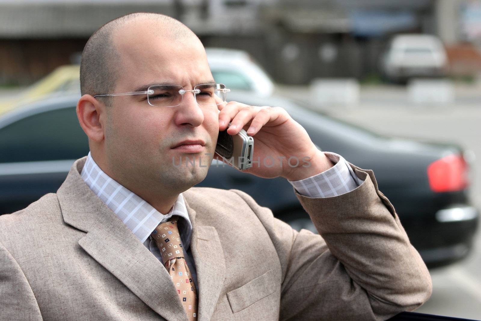 businessman calling by mobile phone, around a luxurious car