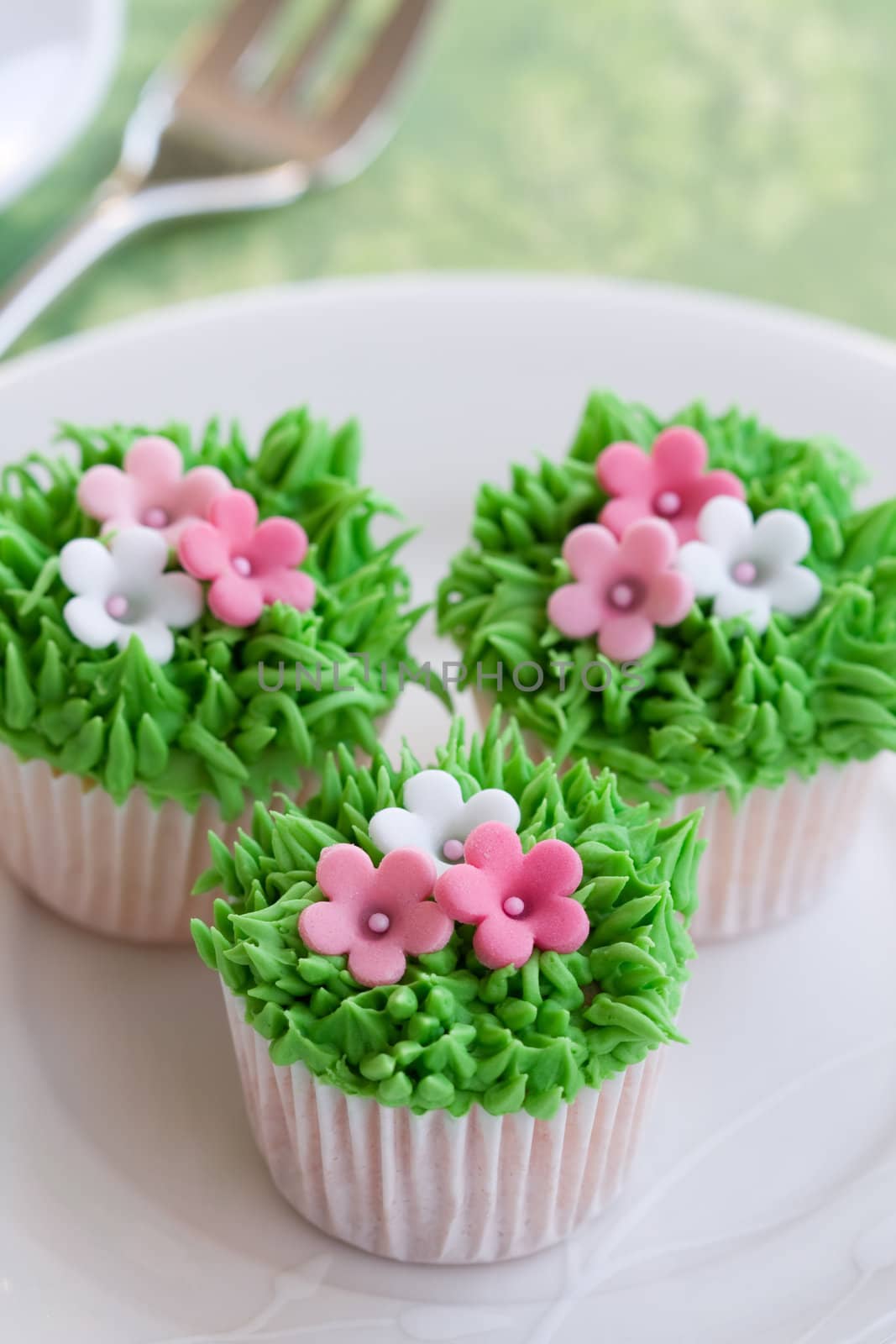 Mini cupcakes decorated with frosted grass and pink flowers