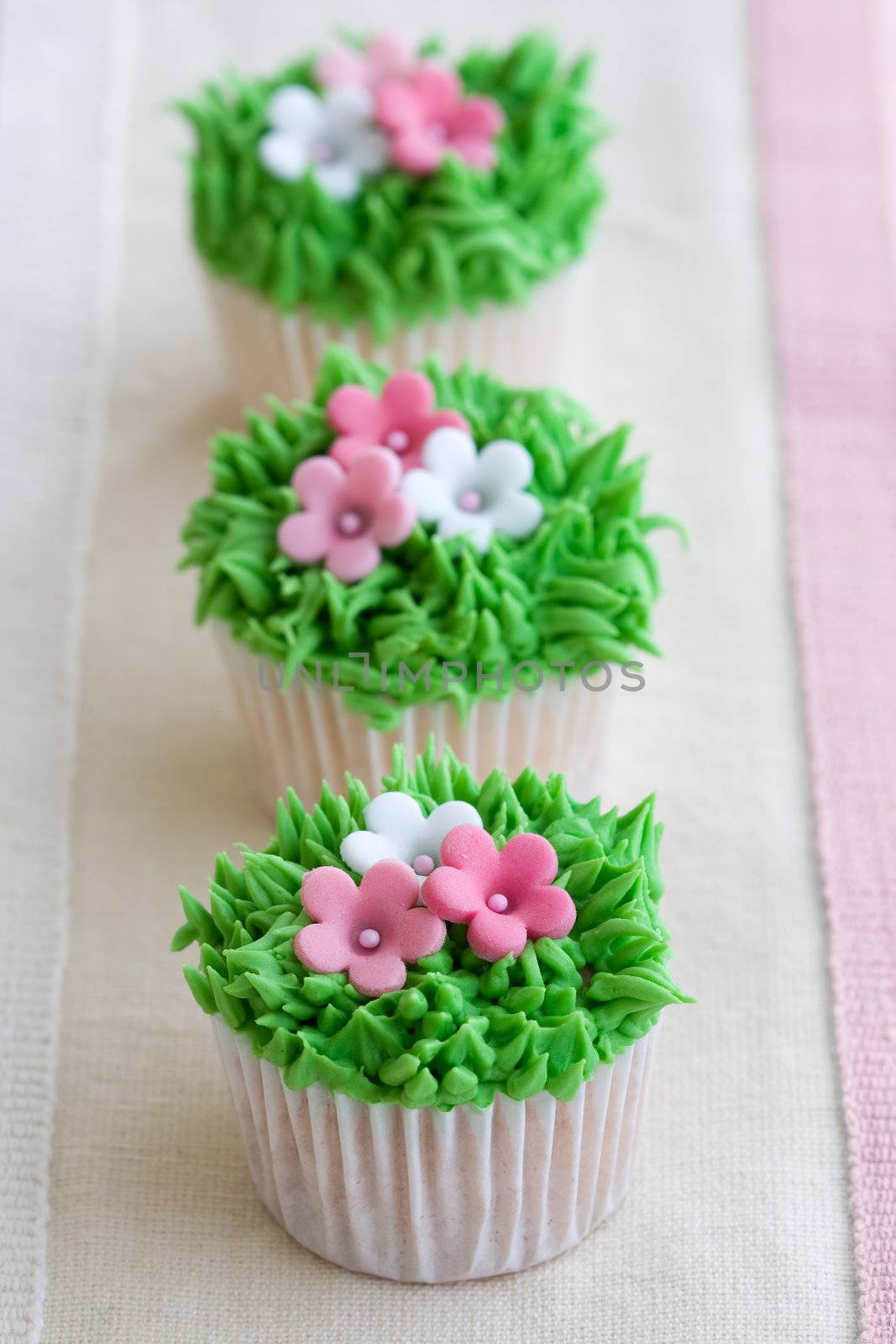 Mini cupcakes decorated with frosted grass and pink flowers