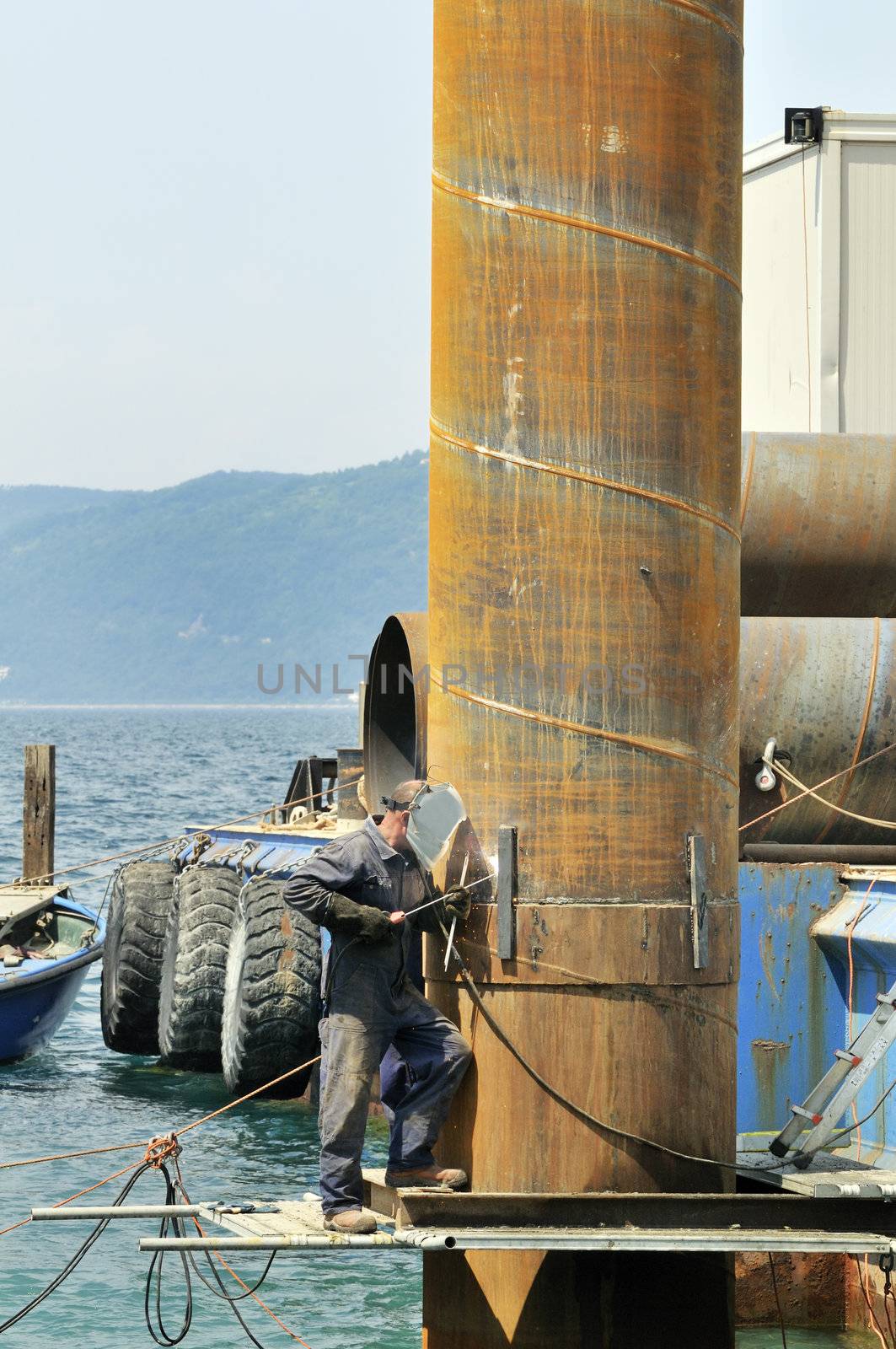 Workman using weld in a harbour
